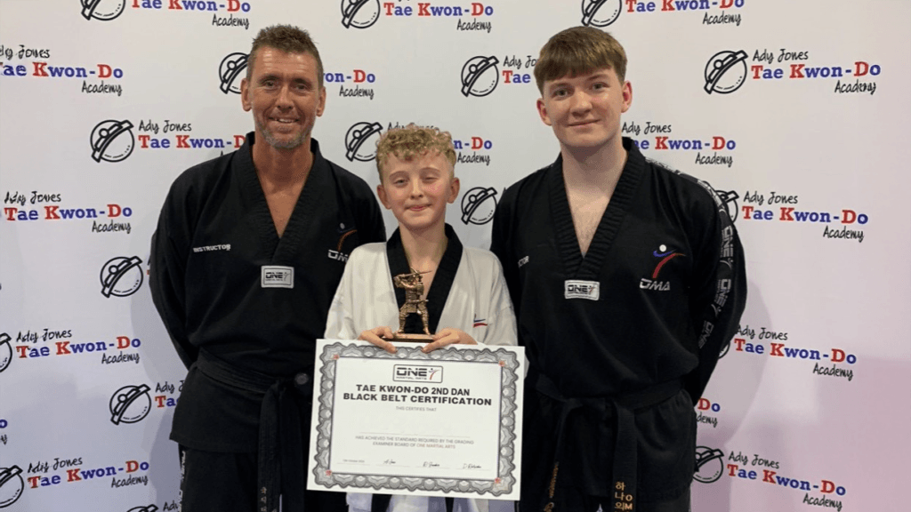 A photo of a student receiving a certificate for Tae Kwon-Do, circa November 2024