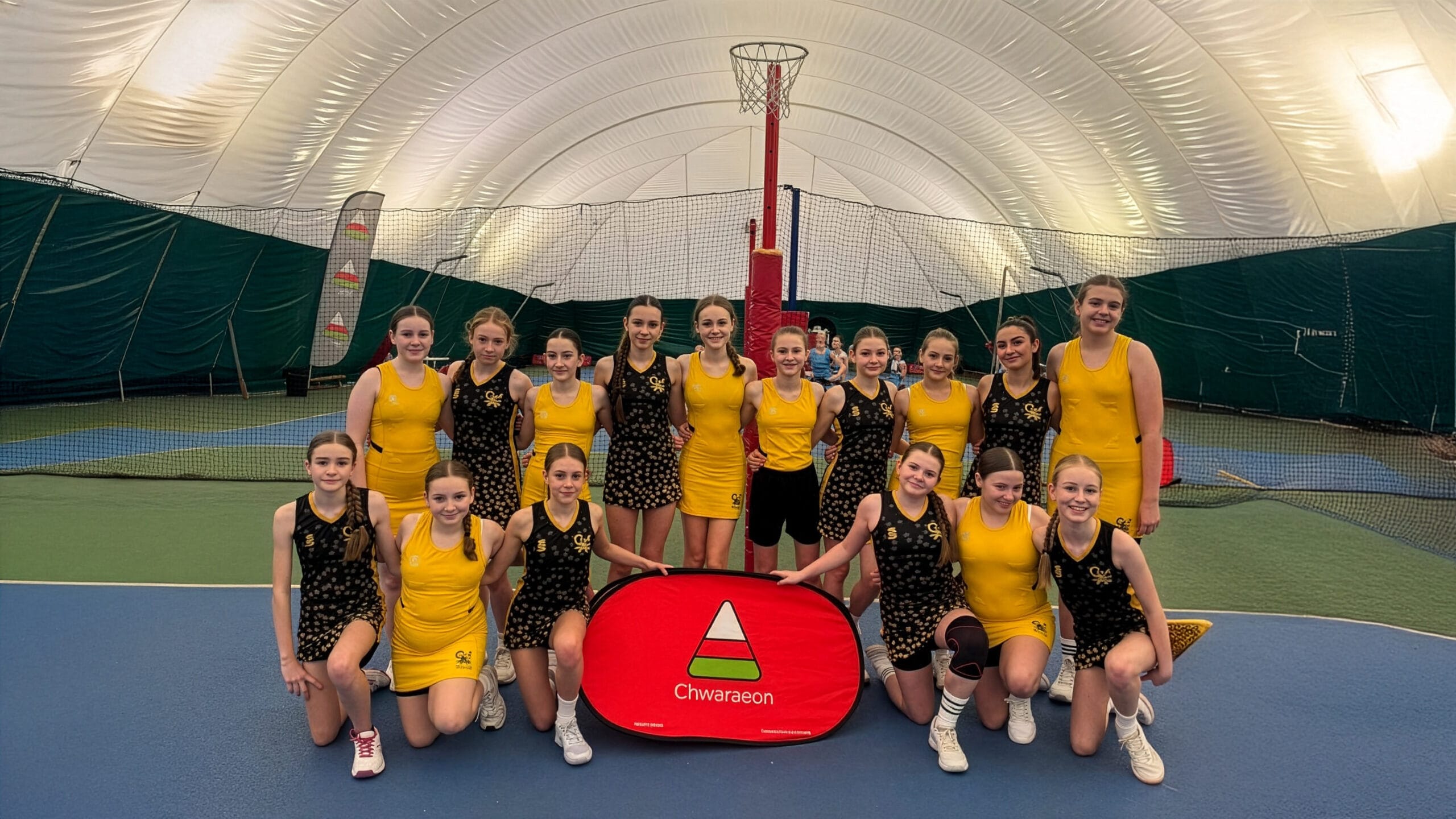 Students posing for a team photo at a netball event, wearing yellow and black kit, circa January 2026