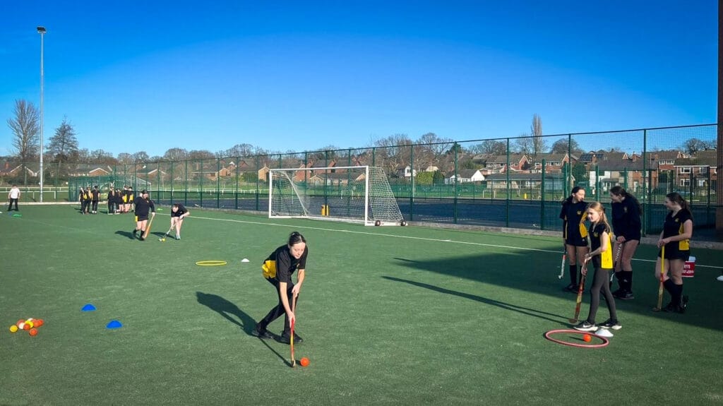 Students taking part in hockey skills practice during a PE lesson on the school's outdoor pitch, circa January 2026
