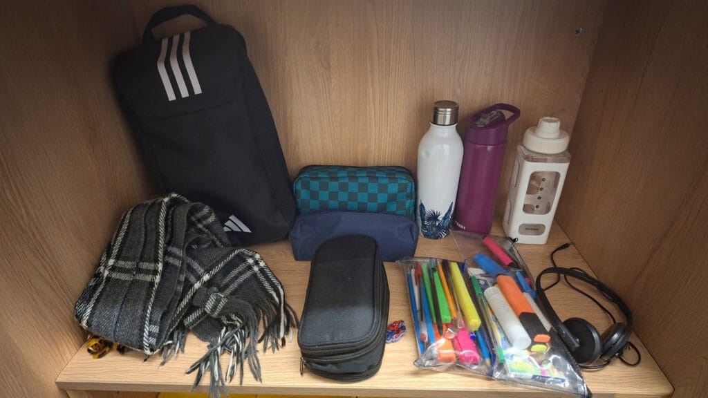 Unclaimed items displayed on a shelf as part of the school's lost property system, including a bag, scarf, bottles and stationery, circa January 2026