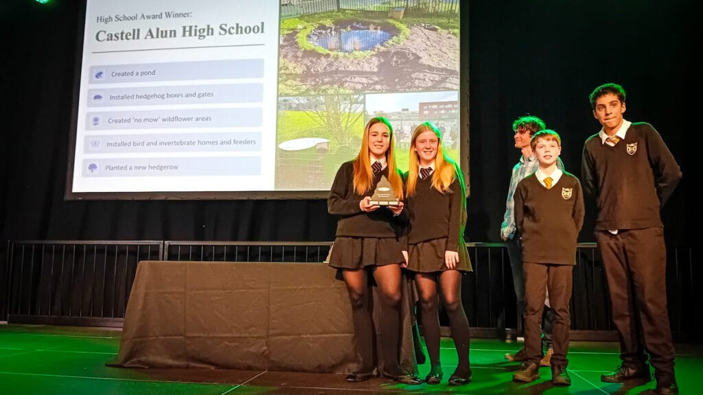 Students from Castell Alun High School holding a trophy on stage after being announced as a High School Award winner, circa February 2026