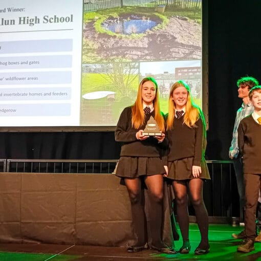 Students from Castell Alun High School holding a trophy on stage after being announced as a High School Award winner, circa February 2026