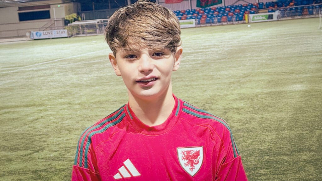 A student wearing a Wales football shirt photographed on a football pitch, circa February 2026