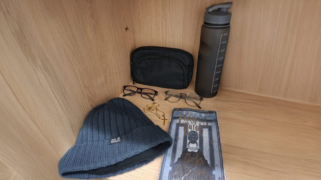 Lost property items on a shelf including a hat, glasses, a water bottle, and a copy of ‘A Christmas Carol’, circa February 2026