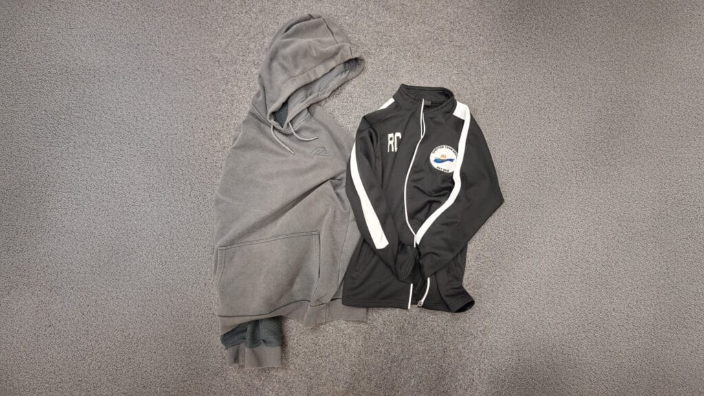 Unclaimed clothing laid out for lost property including a grey hoodie and a black sports jacket, circa February 2026