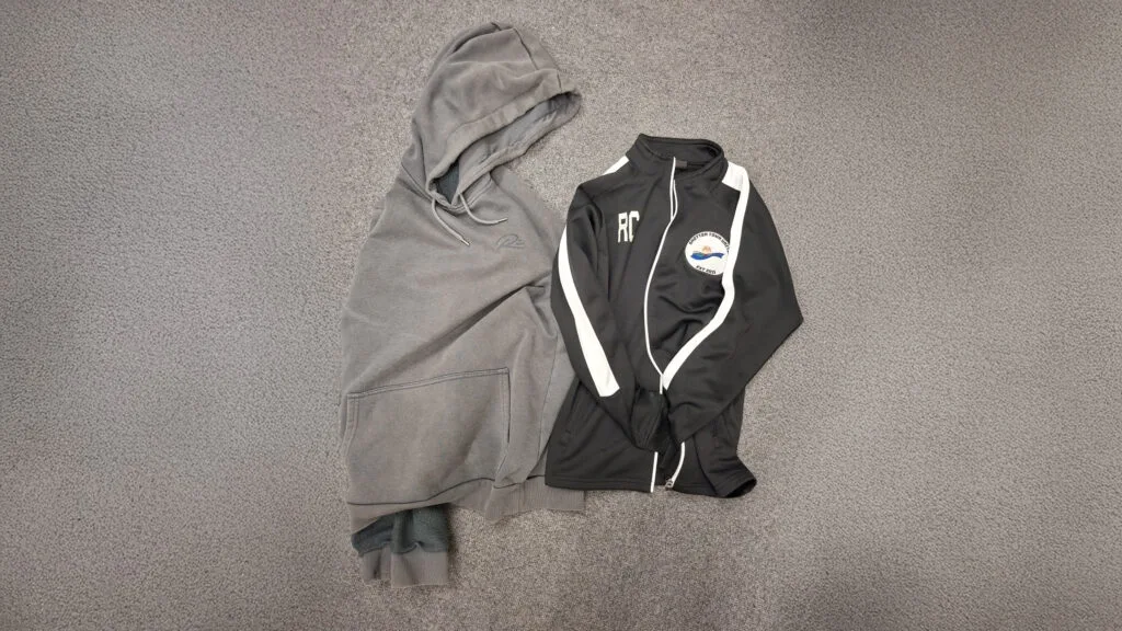 Unclaimed clothing laid out for lost property including a grey hoodie and a black sports jacket, circa February 2026