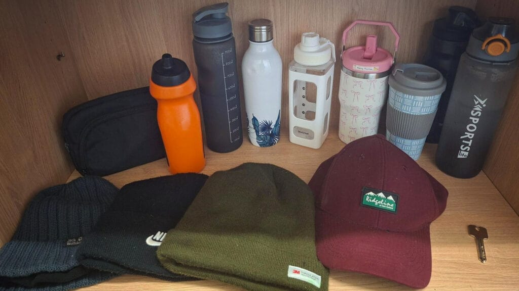 A wooden shelf with assorted water bottles, hats and a single key, shown as lost property, circa February 2026