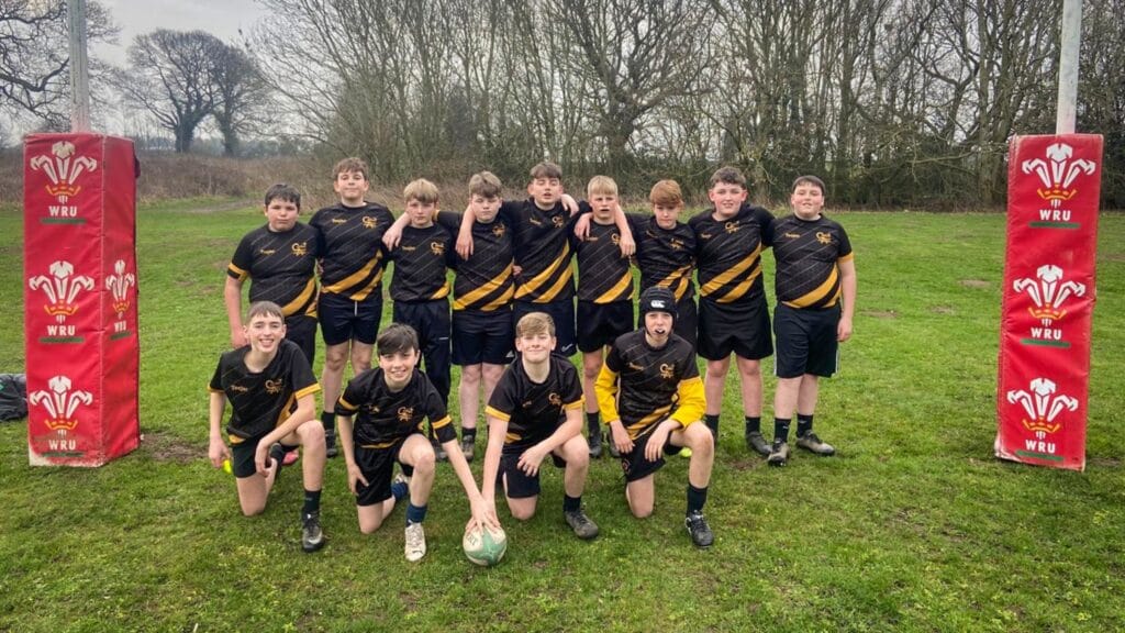 Boys' rugby team group photo on the pitch between WRU goalpost pads, circa March, 2026