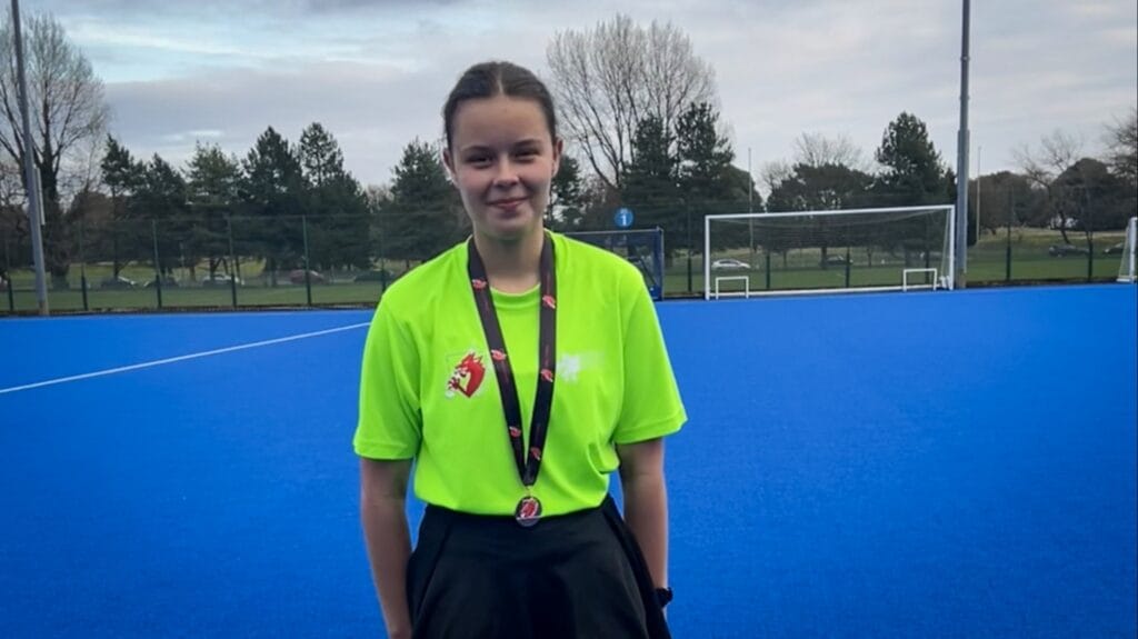 Student wearing a medal on the blue hockey pitch after a sporting event, circa March, 2026