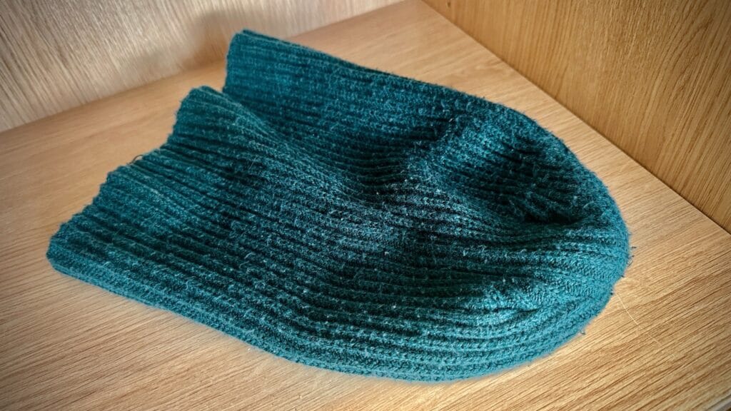 Green knitted hat displayed on a wooden shelf as part of a lost property photograph, circa March, 2026