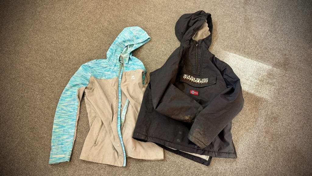 Two coats laid out on the floor, including a blue and grey jacket and a black Napapijri coat, as part of a lost property photograph, circa March, 2026