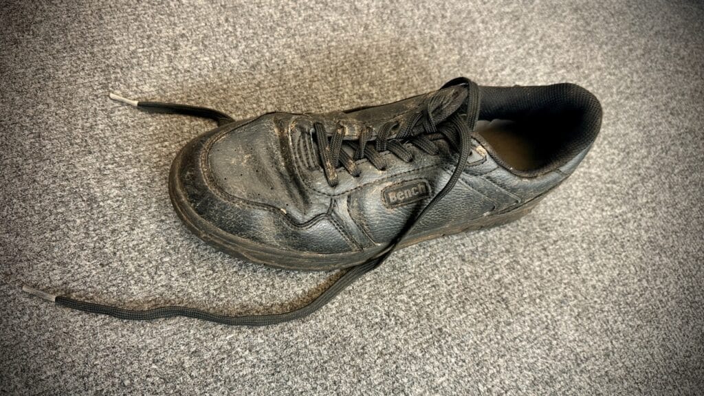 Single black school shoe photographed on a carpet as part of a lost property collection, circa March, 2026