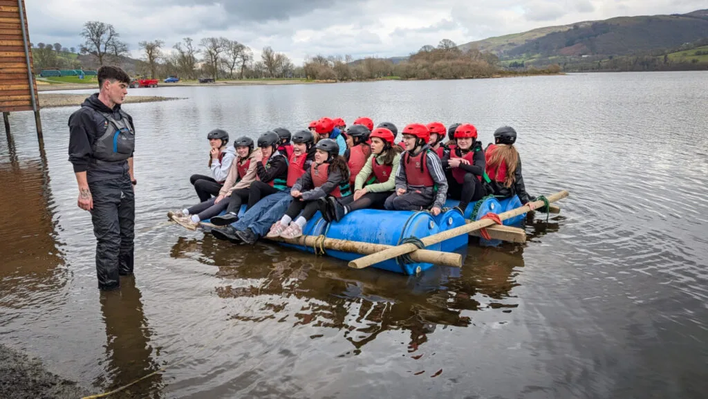 Students sitting on a homemade raft in the lake with an instructor standing nearby, circa March, 2026