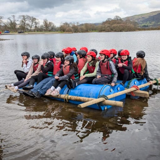Students sitting on a homemade raft in the lake with an instructor standing nearby, circa March, 2026