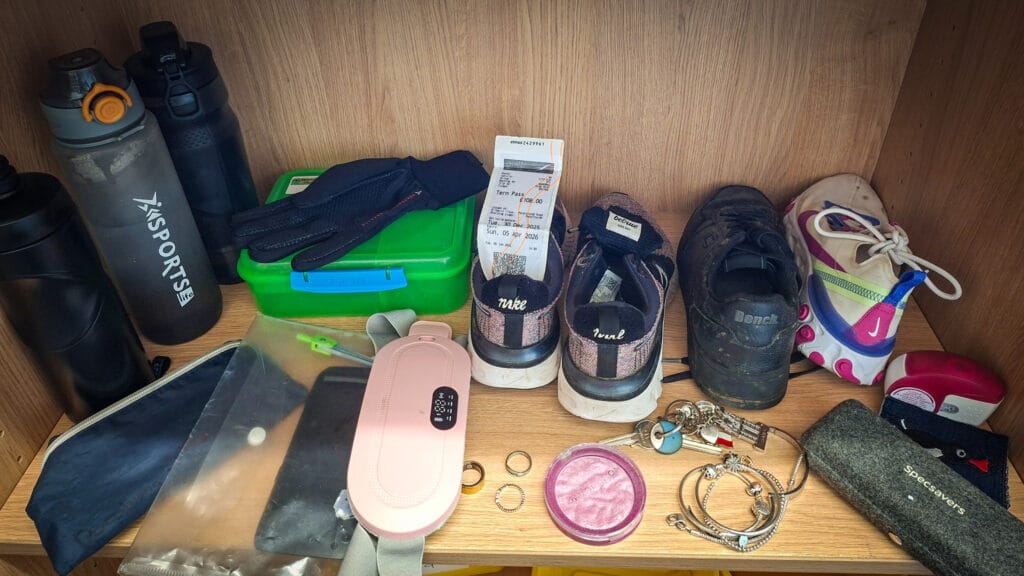 A lost property shelf displaying water bottles, a lunch box, gloves, shoes, jewellery, glasses case and other collected items, circa March, 2026