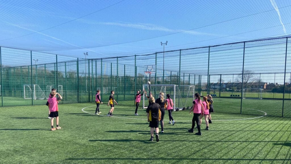 Students taking part in an outdoor netball game on the school sports pitch, circa March, 2026
