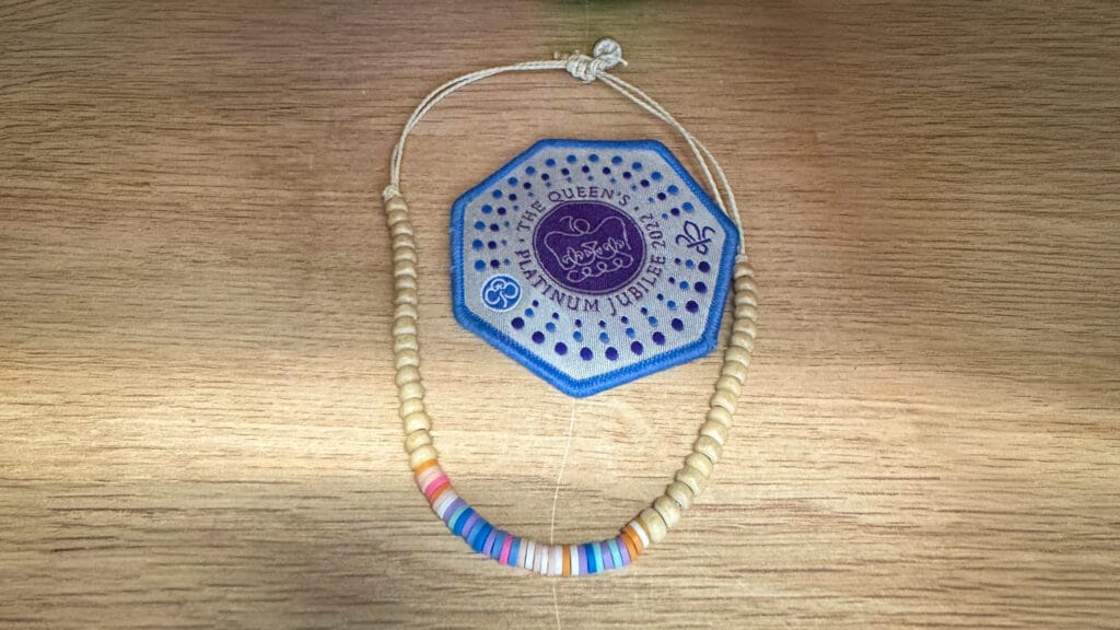 A colourful beaded bracelet and a blue commemorative badge displayed on a wooden surface as part of the school’s lost property collection