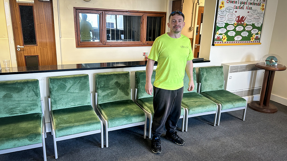 Freshly restored green reception chairs in school reception, with a Carlick Contract Furniture representative beside them.