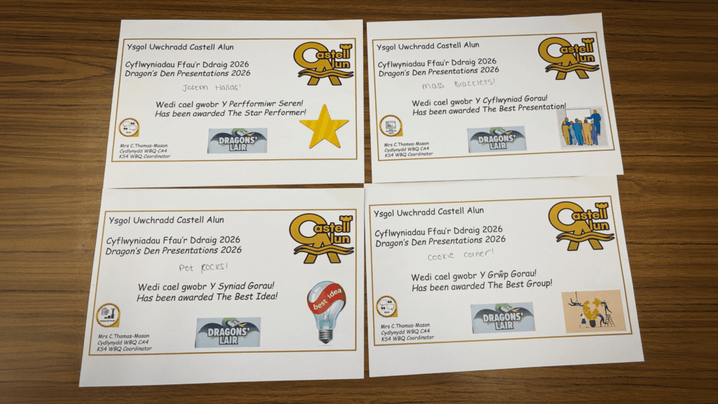 Four certificates from Ysgol Uwchradd Castell Alun for ‘Dragon’s Den Presentations 2026,’ awarding categories such as Star Performer, Best Presentation, Best Idea, and Best Group, laid out on a wooden table.