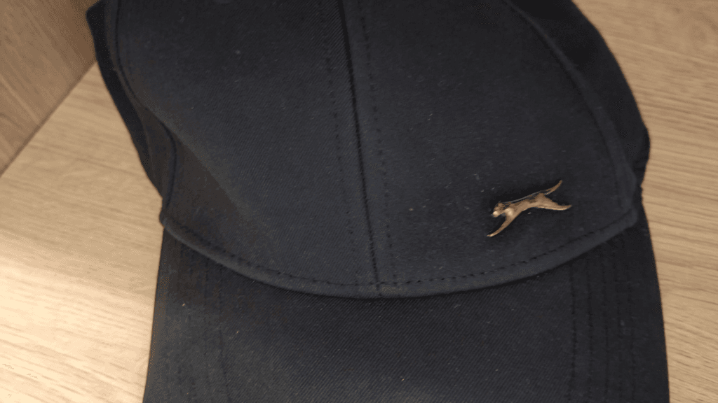 Close-up of a black baseball cap decorated with a small fox pin.