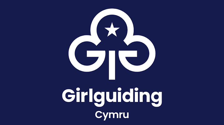 Girlguiding Cymru logo displayed in white against a dark blue background.